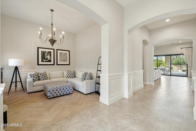 living room with recessed lighting, arched walkways, wainscoting, a decorative wall, and a chandelier