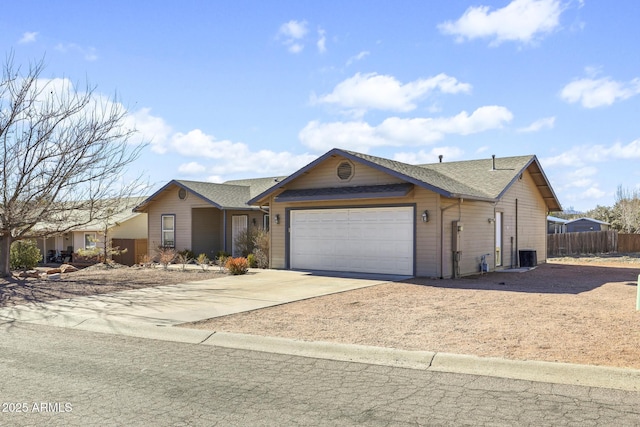 ranch-style house with roof with shingles, concrete driveway, central AC, fence, and a garage