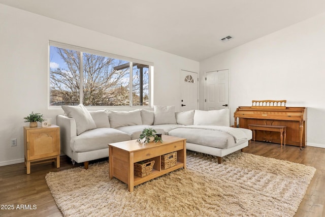 living room with visible vents, vaulted ceiling, baseboards, and wood finished floors