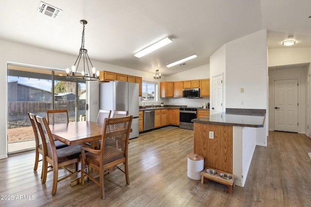 dining room featuring a chandelier, lofted ceiling, visible vents, and wood finished floors