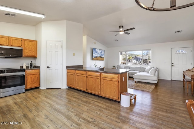 kitchen with a peninsula, wood finished floors, open floor plan, stainless steel electric range oven, and dark countertops