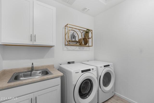 washroom featuring cabinets, washing machine and dryer, light hardwood / wood-style flooring, and sink