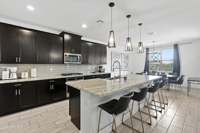 kitchen with pendant lighting, a breakfast bar, a center island with sink, sink, and stainless steel appliances