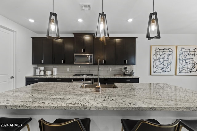 kitchen with dark brown cabinetry, decorative backsplash, sink, and decorative light fixtures