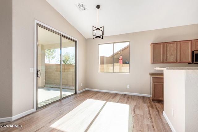 unfurnished dining area with a chandelier, vaulted ceiling, and light wood-type flooring