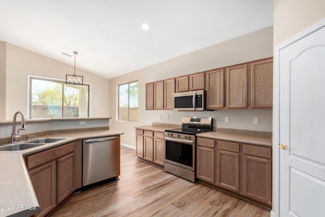 kitchen featuring light wood-type flooring, stainless steel appliances, sink, pendant lighting, and lofted ceiling