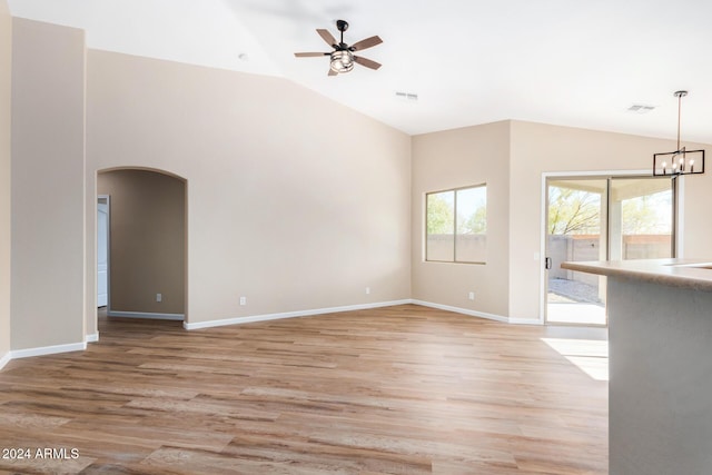 unfurnished living room featuring ceiling fan with notable chandelier, light hardwood / wood-style floors, and lofted ceiling