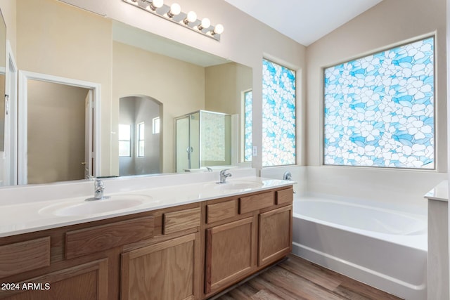 bathroom featuring wood-type flooring, vaulted ceiling, and a healthy amount of sunlight