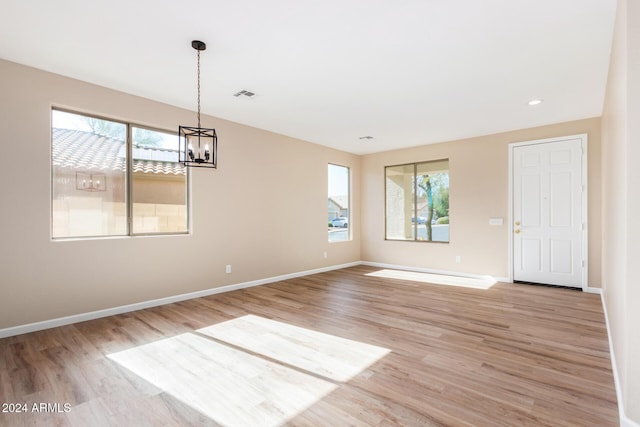 unfurnished room featuring light wood-type flooring and a notable chandelier