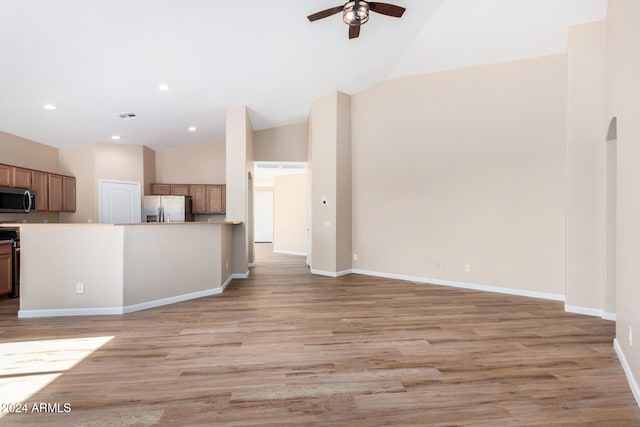 unfurnished living room featuring high vaulted ceiling, light hardwood / wood-style flooring, and ceiling fan