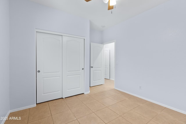 unfurnished bedroom with ceiling fan, a closet, light tile patterned flooring, and baseboards