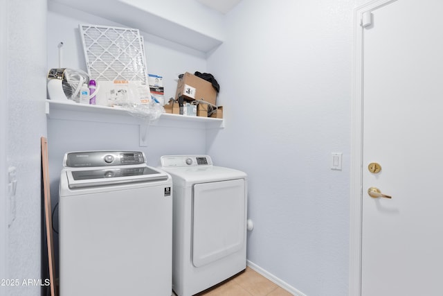 washroom featuring laundry area, baseboards, washer and clothes dryer, and light tile patterned flooring