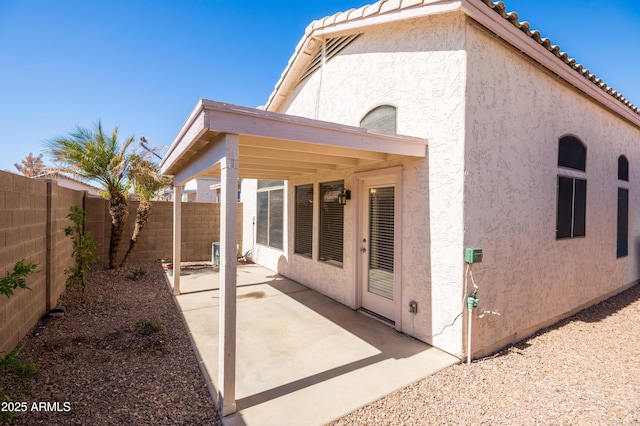 rear view of property with a tile roof, a patio, a fenced backyard, and stucco siding