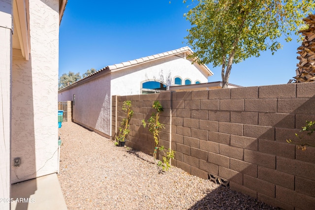 view of side of home with fence and stucco siding