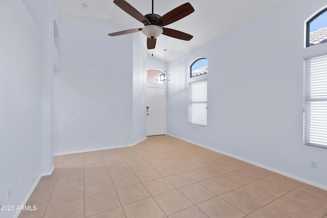 unfurnished room with lofted ceiling, a healthy amount of sunlight, ceiling fan, and baseboards