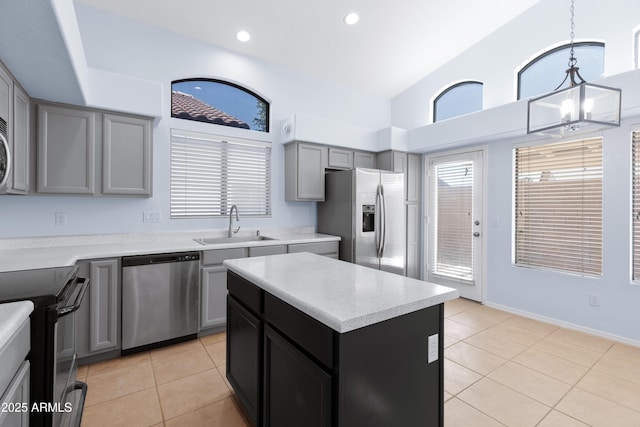 kitchen featuring light tile patterned floors, a center island, stainless steel appliances, light countertops, and gray cabinetry