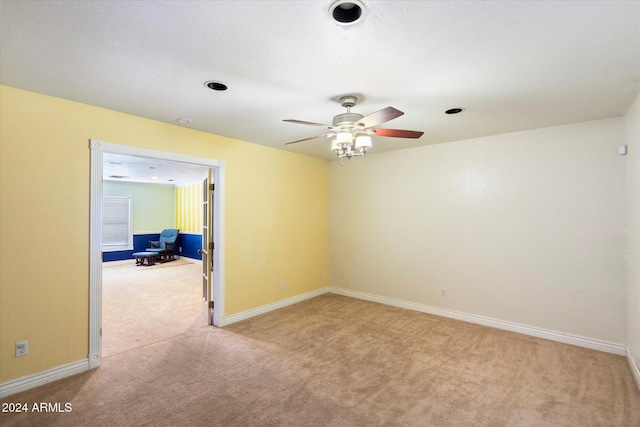 empty room featuring baseboards, a ceiling fan, and light colored carpet