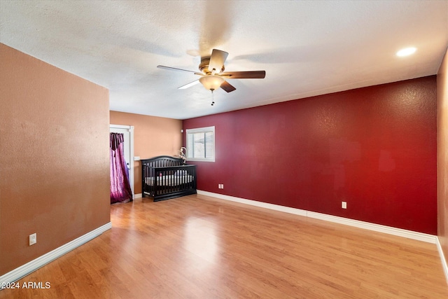 spare room featuring light wood finished floors, a textured ceiling, baseboards, and a ceiling fan