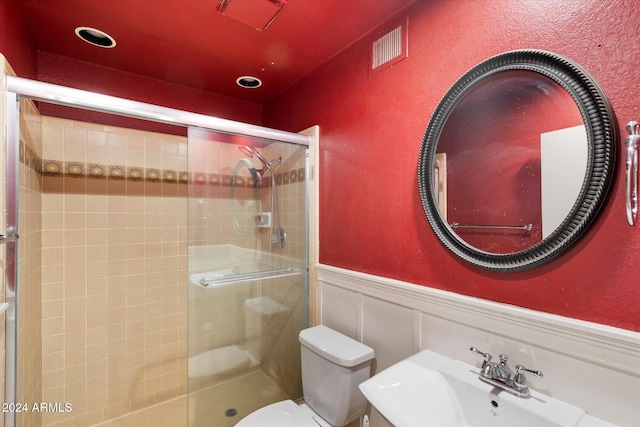 full bath featuring a stall shower, visible vents, toilet, a wainscoted wall, and a sink