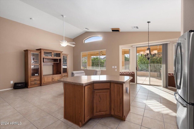 kitchen with ceiling fan with notable chandelier, vaulted ceiling, light tile patterned floors, pendant lighting, and stainless steel refrigerator