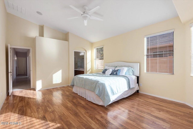 bedroom with hardwood / wood-style floors, ceiling fan, ensuite bathroom, and vaulted ceiling