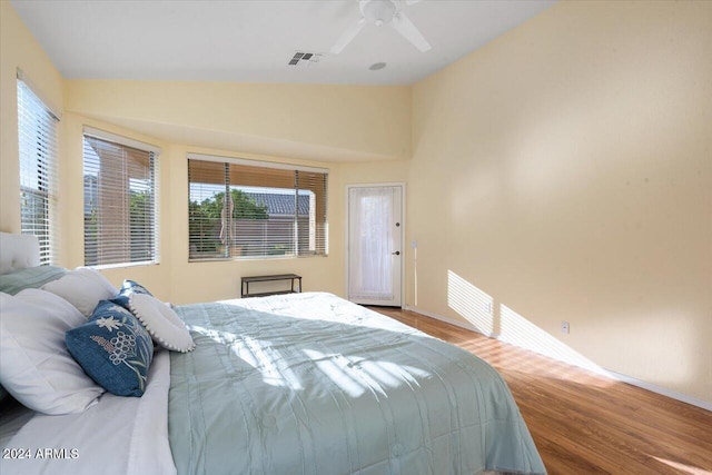 bedroom with ceiling fan, lofted ceiling, wood-type flooring, and multiple windows