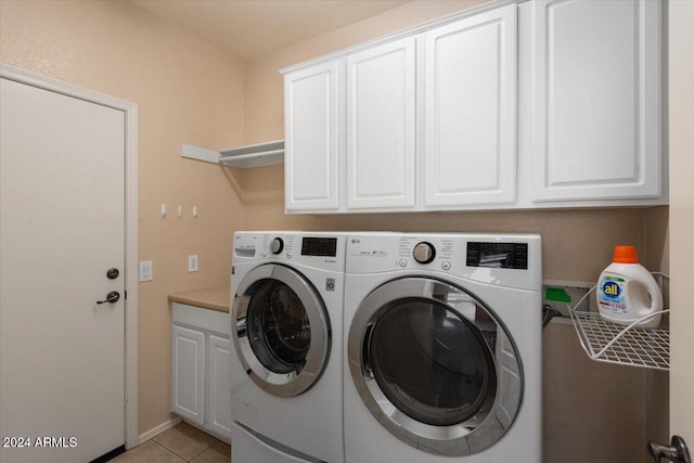 laundry room with washing machine and clothes dryer, light tile patterned flooring, and cabinets