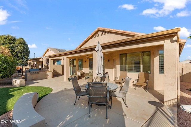 back of property featuring ceiling fan, area for grilling, and a patio area