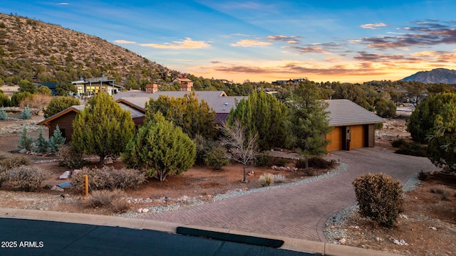 view of front of home with driveway, a garage, a chimney, a tiled roof, and a mountain view