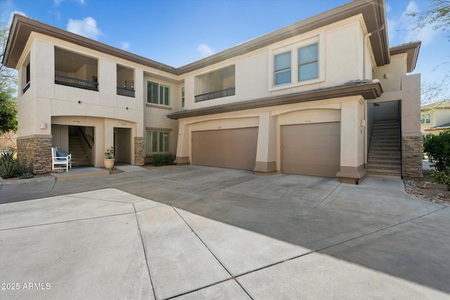 view of front of home featuring stucco siding, driveway, stone siding, a garage, and stairs