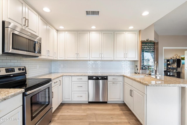 kitchen featuring appliances with stainless steel finishes, a peninsula, and white cabinetry