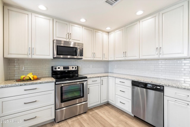 kitchen featuring visible vents, stainless steel appliances, decorative backsplash, white cabinetry, and light wood-type flooring