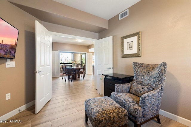 living area with visible vents, light wood-style flooring, and baseboards