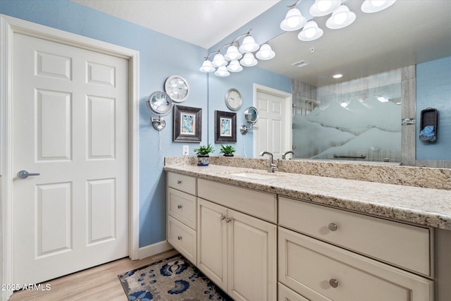 full bath featuring baseboards, vanity, walk in shower, and wood finished floors