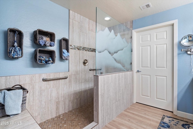 bathroom with visible vents, a walk in shower, tile walls, and wood finished floors