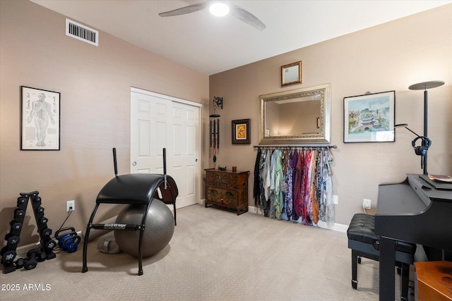 exercise area with visible vents, baseboards, light colored carpet, and ceiling fan