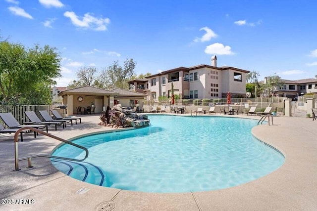 community pool featuring a patio, fence, and a residential view