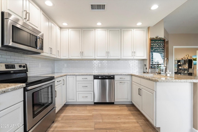 kitchen with white cabinetry, a peninsula, and stainless steel appliances