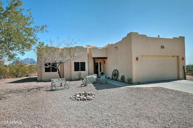 pueblo-style home featuring stucco siding, driveway, and an attached garage