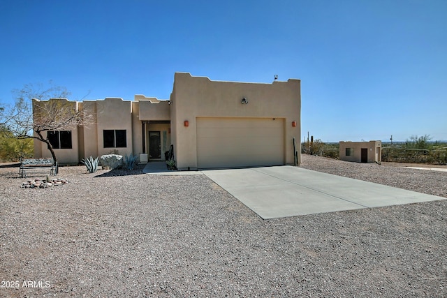 southwest-style home with stucco siding, a garage, and driveway