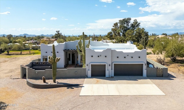 southwest-style home featuring driveway, a garage, fence, and stucco siding