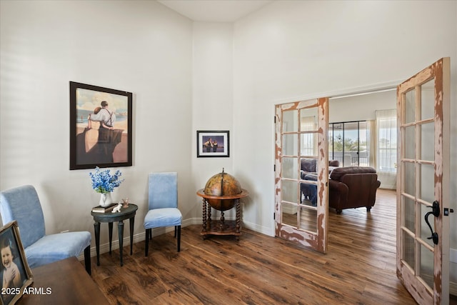 sitting room featuring a high ceiling, baseboards, wood finished floors, and french doors