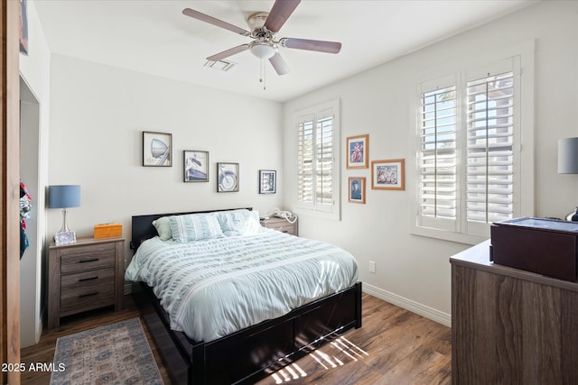 bedroom featuring a ceiling fan, baseboards, visible vents, and wood finished floors