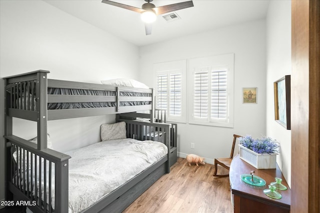 bedroom with baseboards, visible vents, and wood finished floors