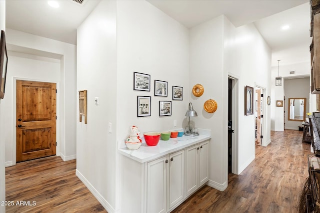 corridor featuring visible vents, baseboards, and wood finished floors