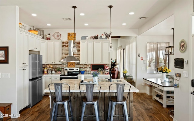 kitchen with visible vents, wall chimney exhaust hood, appliances with stainless steel finishes, dark wood-style flooring, and backsplash