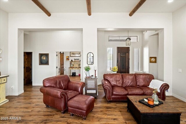 living area with wood finished floors, beam ceiling, and baseboards