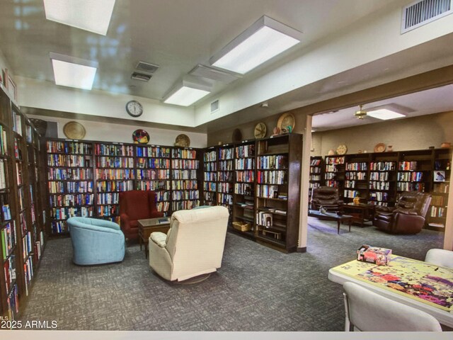 7970 E Camelback Rd Unit 110, Scottsdale, AZ 85251 - living area featuring visible vents, bookshelves, and carpet
