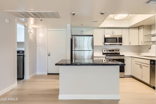 7970 E Camelback Rd Unit 110, Scottsdale, AZ 85251 - kitchen with a kitchen island, baseboards, a sink, light wood-style flooring, and stainless steel appliances