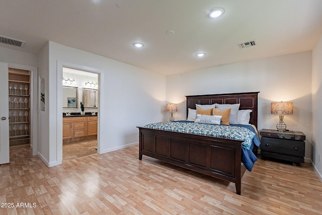 bedroom featuring ensuite bathroom and light hardwood / wood-style floors